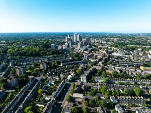 Aerial view of croydon, south london, featuring residential houses, green spaces, and the skyline on a clear, sunny day